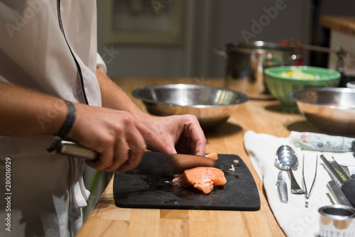 Mains de cuisinier qui découpe du poisson
