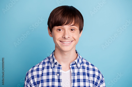 Portrait of charming boy looking wearing checked shirt isolated over blue background