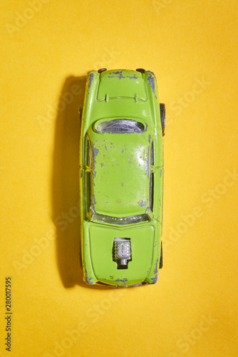 Vintage model of a children's car photographed from above in green on a yellow background