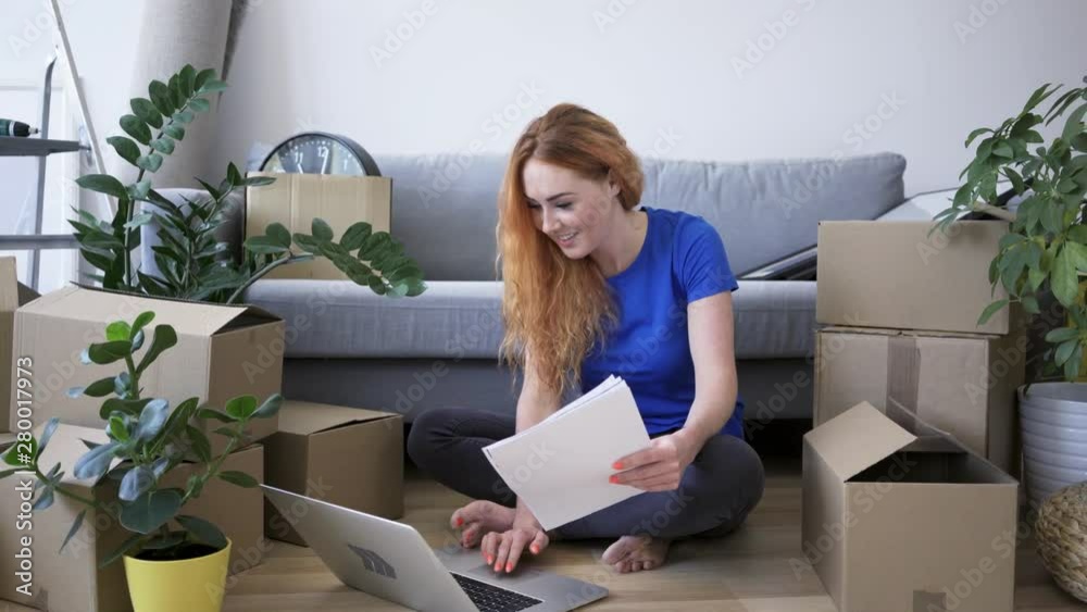 Young woman using laptop palanning new apartment while moving in Young woman using laptop palanning new apartment while moving in