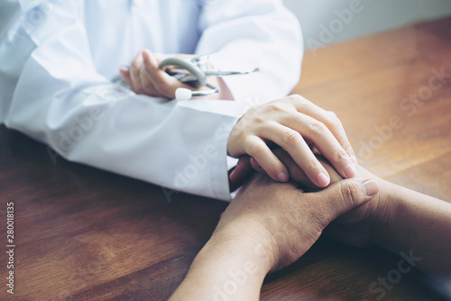 Female psychiatrist touching on stress patient man hands to cheer up him from sadness in clinic hospital health ideas concept