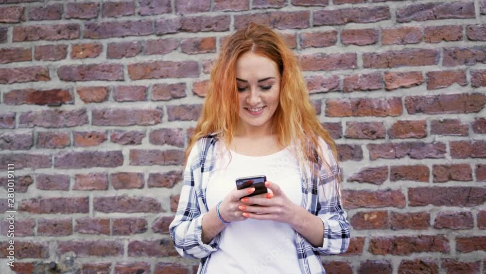 Cheerful young woman using phone while standing outdoors Cheerful young woman using phone while standing outdoors