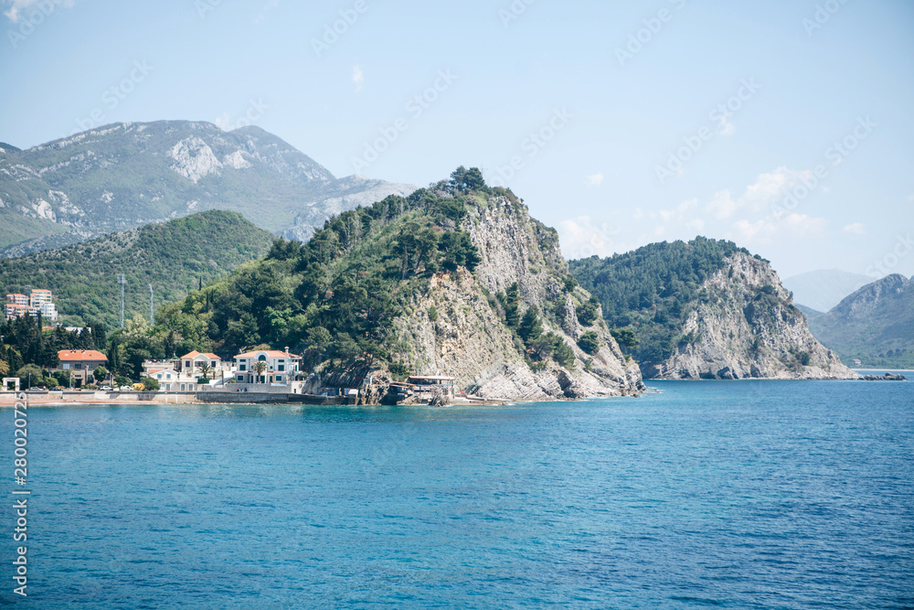 Beautiful view of the natural landscape. View of the mountains, the sea and near them buildings or residential buildings in Petrovac in Montenegro.