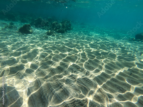 Underwater view of sea bottom with sand, rocks and stones..