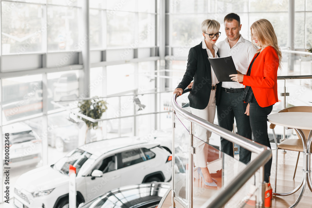 Φωτογραφία Couple standing hugging in interior of dealership with dealer