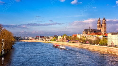 View of Magdeburg with cathedral, river Elbe and cargo boat, beautiful bright morning cityscape with blue sky and clouds, Saxony, Germany. Outdoor travel background
