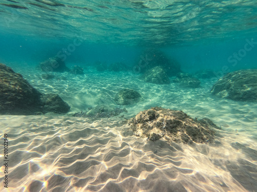 Underwater view of sea bottom with sand, rocks and stones..