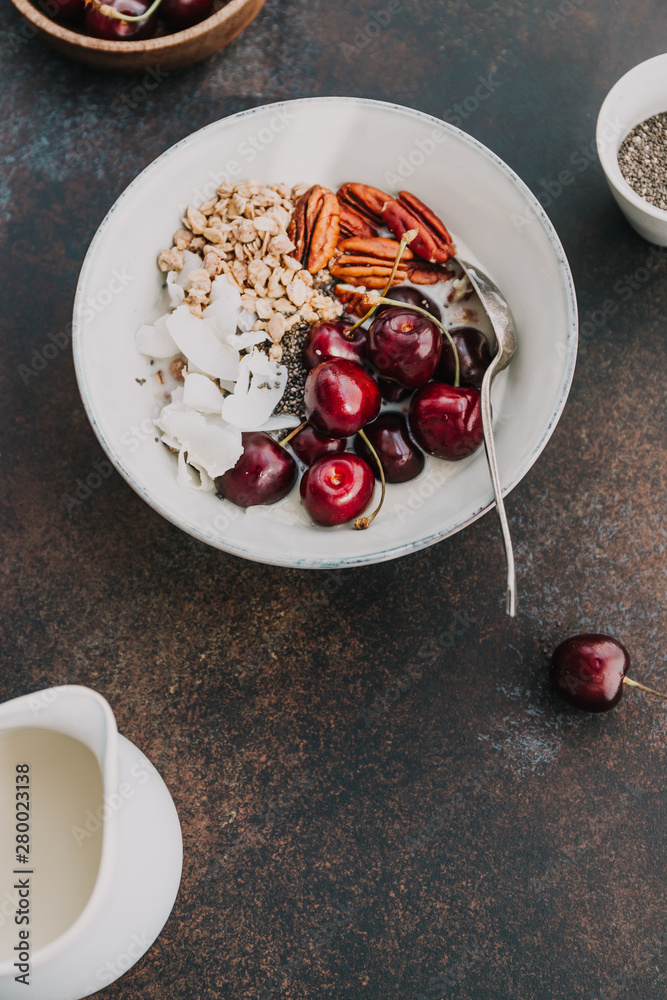Healthy summer vegetarian breakfast with granola, cherry, pecans, coconut flakes, chia and oat milk. Flat lay, top view. Healthy summer vegetarian breakfast with granola, cherry, pecans, coconut flakes, chia and oat milk. Flat lay, top view.