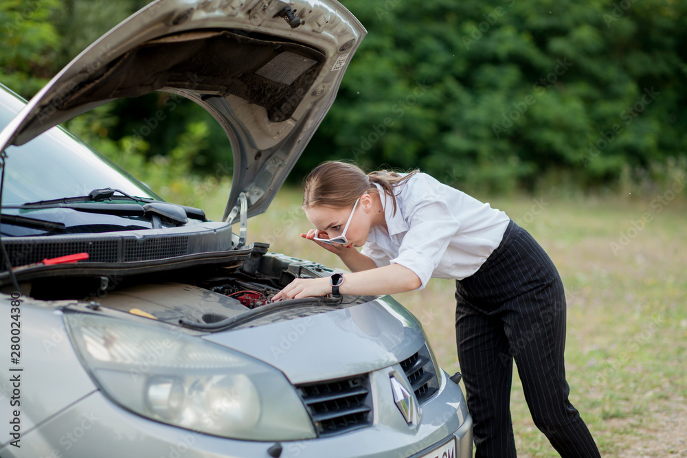 Young woman by the roadside after her car has broken down She opened the hood to see the damage Young woman by the roadside after her car has broken down She opened the hood to see the damage