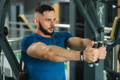 A young athlete trains in the gym. Bodybuilder trains the muscules of the chest