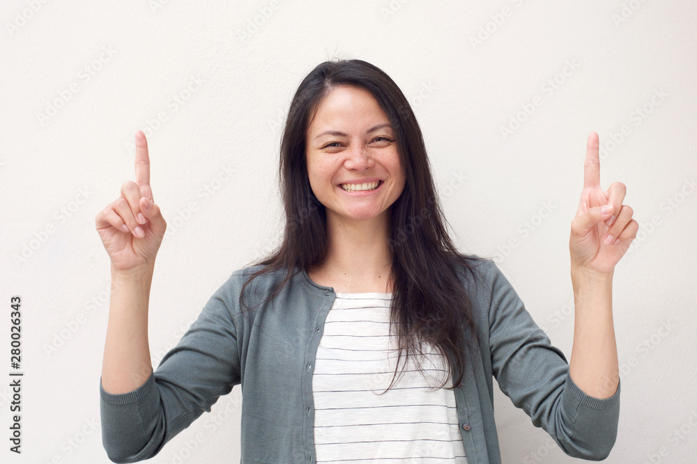 happy asian girl pointing fingers up against white background happy asian girl pointing fingers up against white background