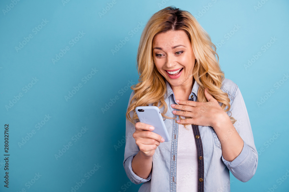 Portrait of astonished funny lady touching her chest screaming holding modern technology isolated over blue background Portrait of astonished funny lady touching her chest screaming holding modern technology isolated over blue background