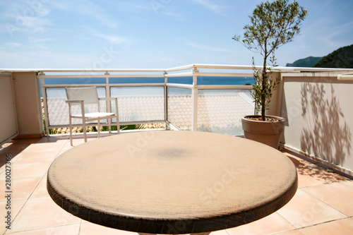 Table background on a beautiful blue sky and ocean view. Empty space on a round wooden table top for an advertising product.