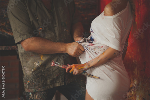  A couple of painters. Female and male hands of the artist with brushes, paints, and a palette for drawing photo