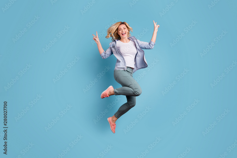 Full size photo of cheerful person jumping moving making v-signs laughing isolated over blue background