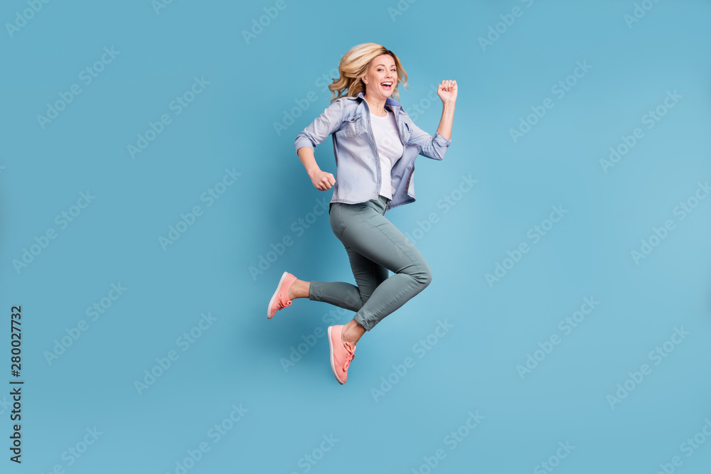 Full length profile side photo of charming lady moving doing activity wearing denim jeans jacket trousers pants isolated over blue background