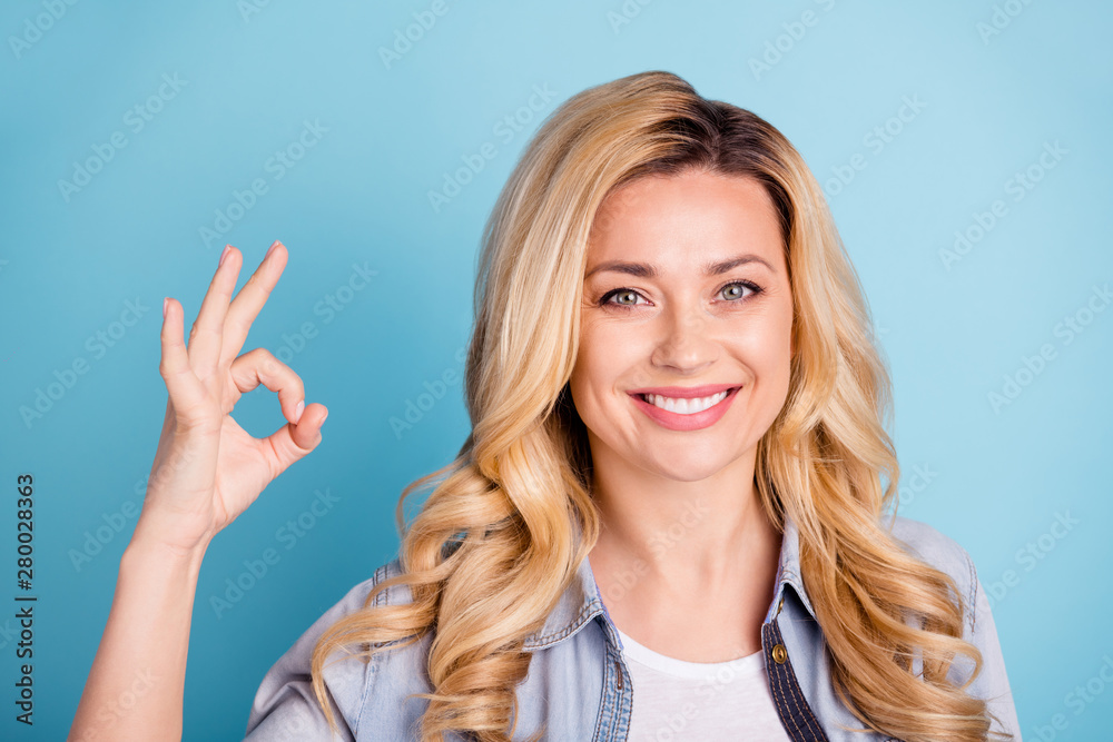 Close up photo of charming person making ok sign with her fingers looking at camera isolated over blue background Close up photo of charming person making ok sign with her fingers looking at camera isolated over blue background