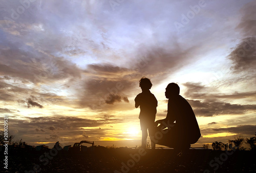 The silhouette of the father and son who enjoyed the sunset for Father's Day love-holiday concept