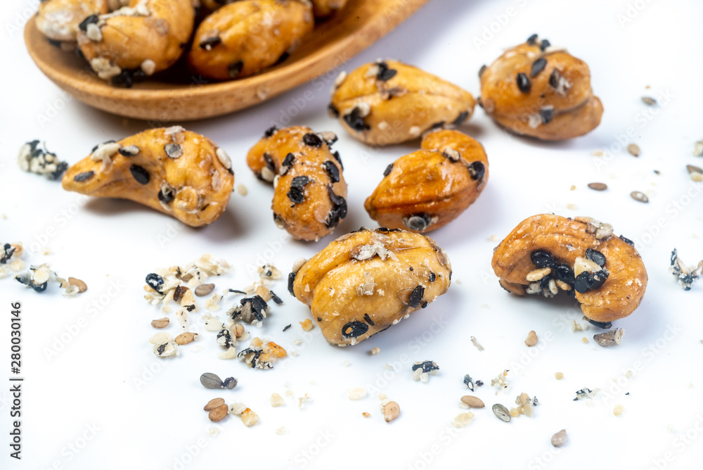 Sesame Coated Cashew Nuts on wooden spoon. Isolated on white background Sesame Coated Cashew Nuts on wooden spoon. Isolated on white background