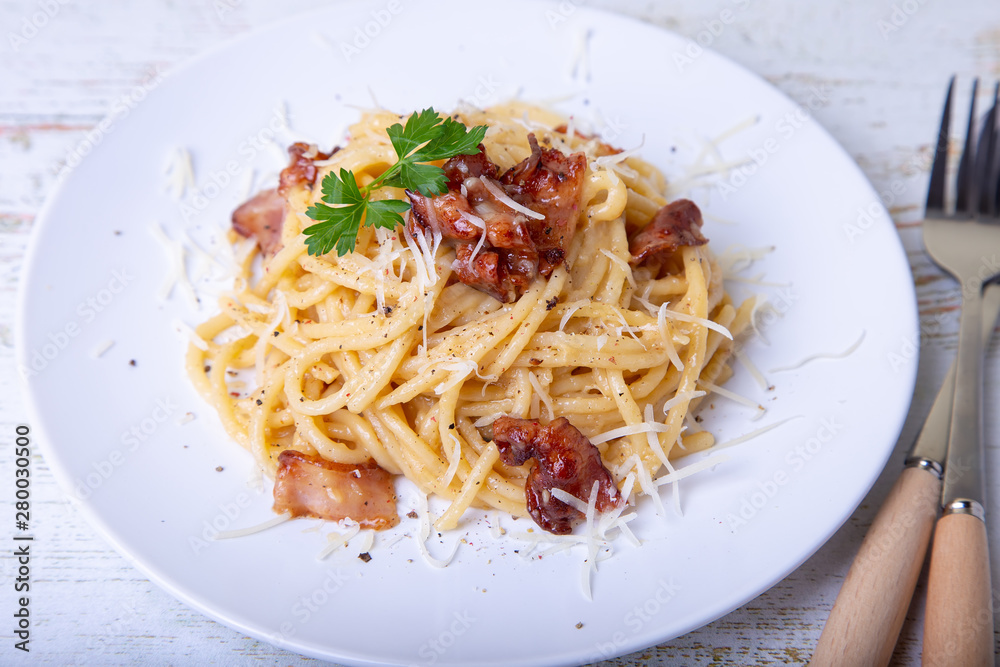 Pasta carbonara with bacon, cheese Parmesan and parsley. Traditional Italian dish. Close-up, selective focus.