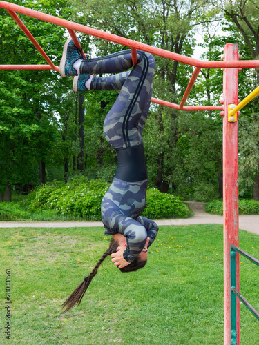 girl trains on the bar ,hanging upside down and shakes the press