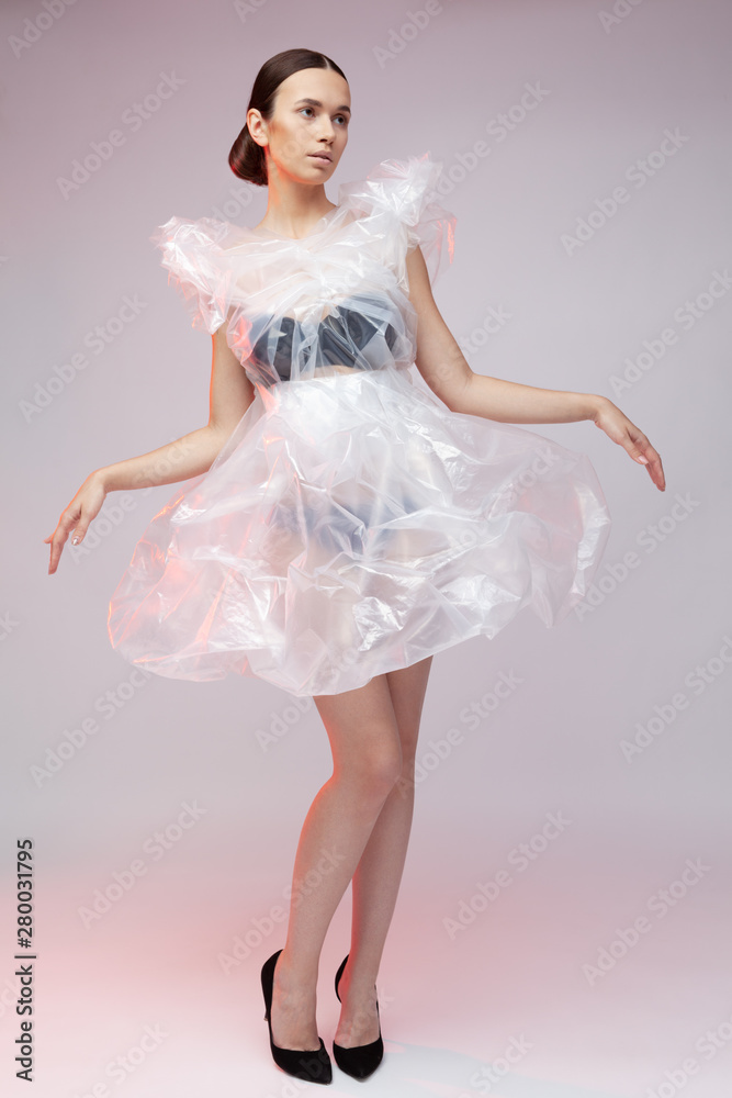 Girl posing in a dress made of plastic film. Fashion portrait. Girl posing in a dress made of plastic film. Fashion portrait.