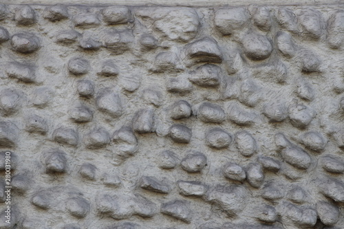 Old grey stone wall with rough blistered texture by inserted round boulders
