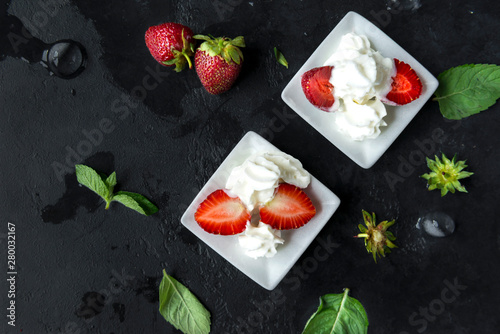 berries fresh strawberries with whipped cream on a black background
