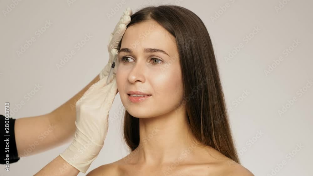Side view of brunette caucasian woman has the beauty injections in her face slow motion Side view of brunette caucasian woman has the beauty injections in her face slow motion