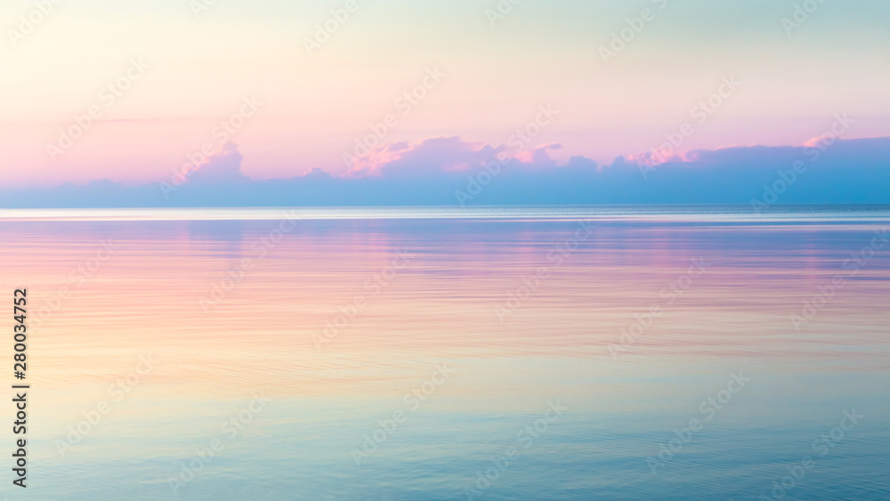 Morning clear seascape with colorful sky. Natural soft background. Beautiful magical pink and gold reflected in the water.