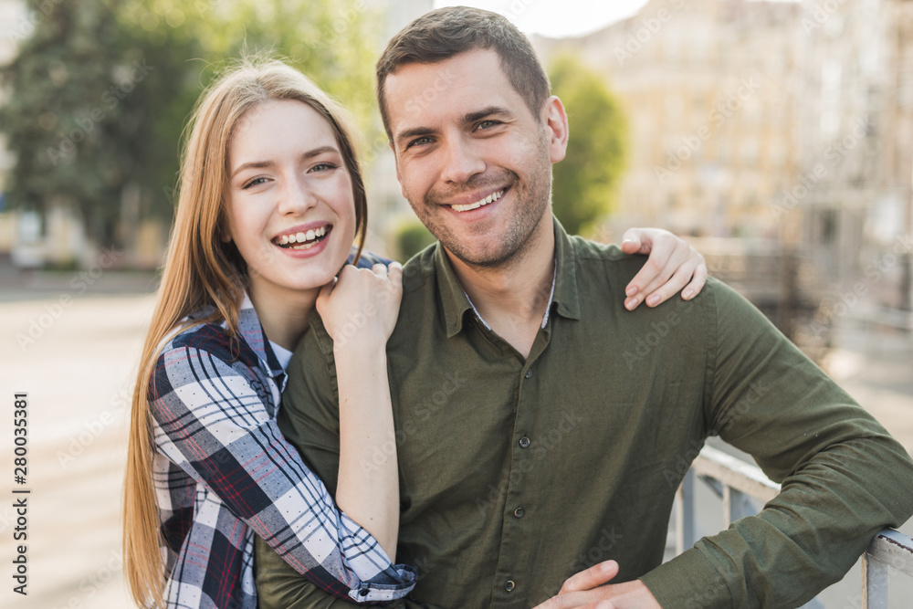Fototapeta premium Young smiling couple standing near railing looking at camera