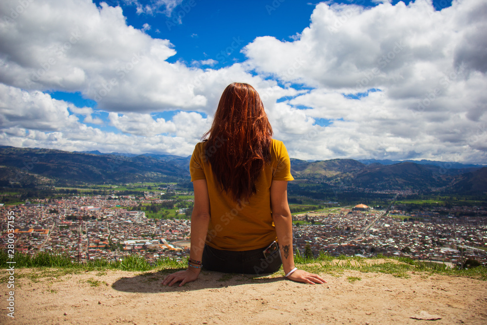 Pelirroja contempla ciudad de Cajamarca cielo azul