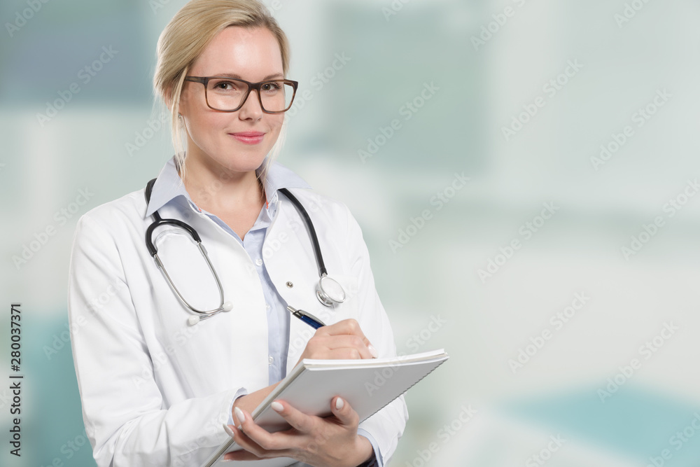 young female friendly doctor with stethoscope writes a prescription - obrazy, fototapety, plakaty 