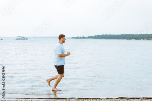 man running by sea beach barefoot © phpetrunina14
