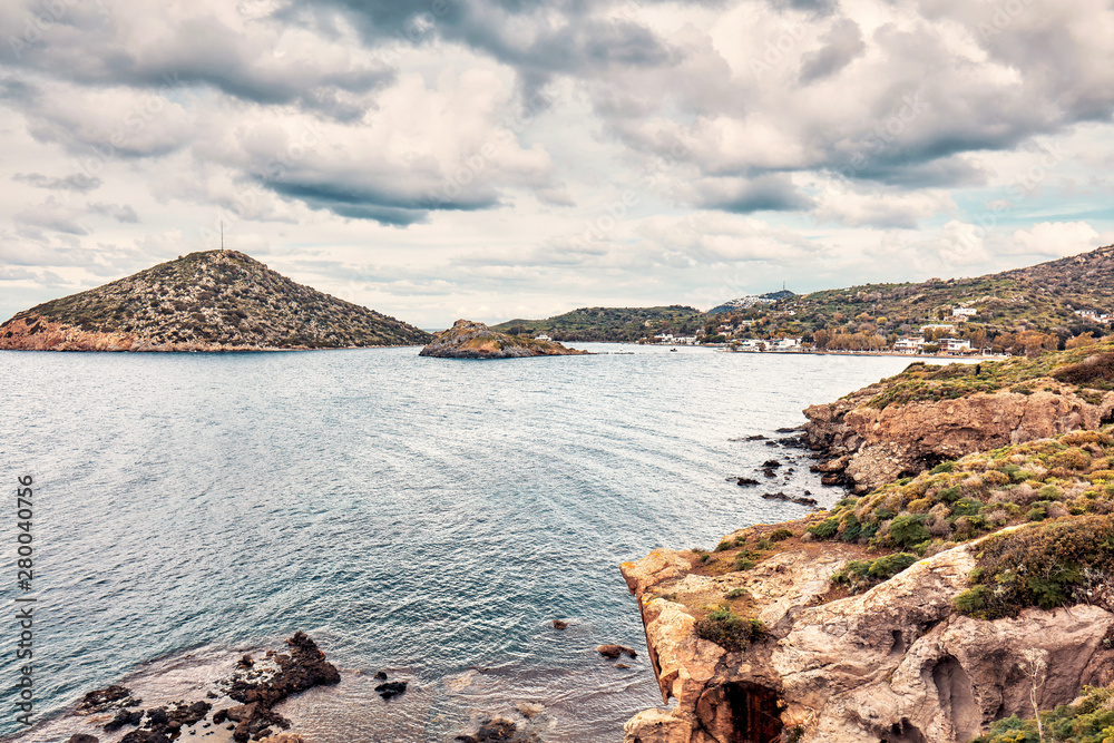 Moody view of Gumusluk bay in Bodrum, Mugla, Turkey on a cloudy winter day. Beautiful calm sea, meadow and sky landscape.