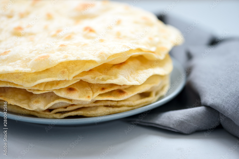 Close up stack of pita, Arabic bread, flatbread on gray wooden background. Soft focus. Traditional arabian food