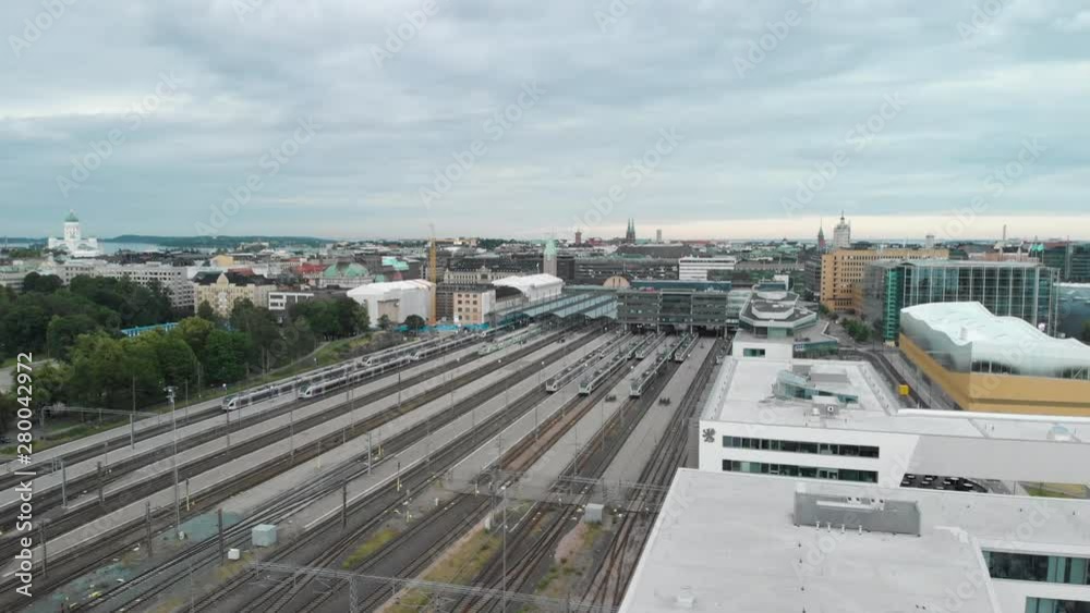 Aerial, drone shot, over buildings, towards the railway tracks at the train station, the Helsinki cathedral and the downtown, in the background, on a cloudy, summer day, in Uusimaa, Finland Aerial, drone shot, over buildings, towards the railway tracks at the train station, the Helsinki cathedral and the downtown, in the background, on a cloudy, summer day, in Uusimaa, Finland