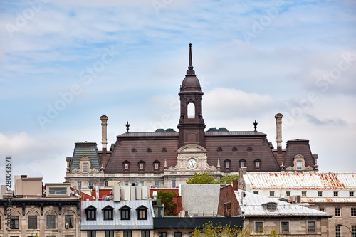 The tower, clock and roof of Montreal city hall hotel de ville against bright cloudy sky in old Montreal, Quebec, Canada photo