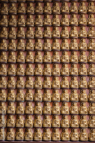 Golden Chinese buddha statue pattern on wall background.