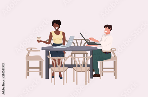 mix race business couple discussing during meeting coffee break concept man woman office workers sitting at table using laptops flat horizontal full length