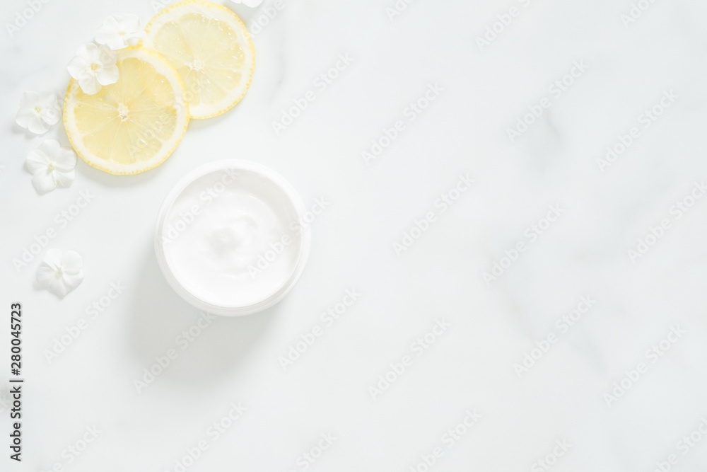 White moisturizing cream with lemon citrus and flower petals on marble background. Skin care beauty treatment with jar of body moisturizer. Bio organic, natur White moisturizing cream with lemon citrus and flower petals on marble background. Skin care beauty treatment with jar of body moisturizer. Bio organic, natur