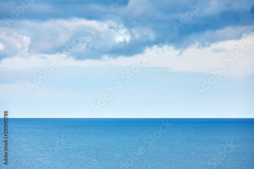Minimalist aerial nature landscape background with calm sea and rain clouds over the sea in the morning at winter time.