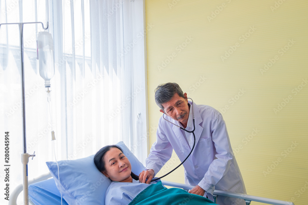 Senior asian male doctor visiting and check-up middle-aged female patient on Ward. in room hospital. concept healthcare and medicine. Senior asian male doctor visiting and check-up middle-aged female patient on Ward. in room hospital. concept healthcare and medicine.