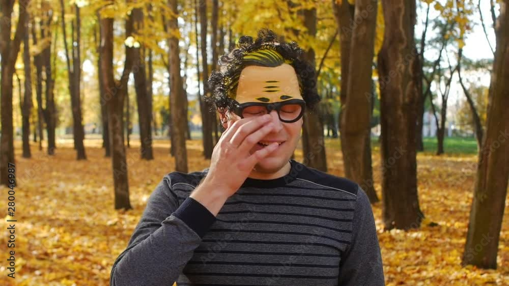 Branch hit the eye of dissatisfied man in a mask in the autumn park. Funny moment Branch hit the eye of dissatisfied man in a mask in the autumn park. Funny moment