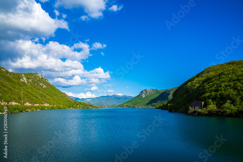 Montenegro  Beauty of water reservoir jezero liverovoci in green valley near niksic city surrounded by green trees and forest covering mountains nature landscape with blue sky