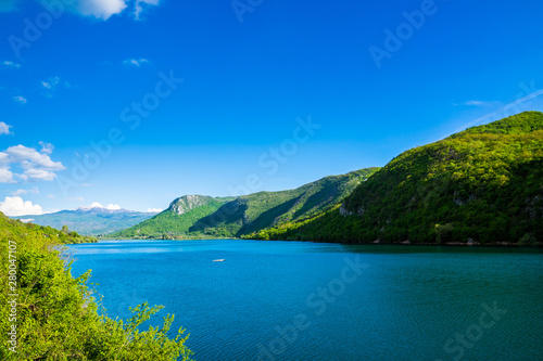 Montenegro  Barrier lake water of jezero liverovoci in a green valley surrounded by trees and forest near niksic city in beautiful nature landscape with blue sky