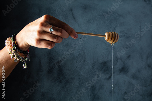 Woman hand holding wooden stick for honey with honey