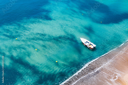 Fototapeta Naklejka Na Ścianę i Meble -  Aerial view of a boat on water and sandy coastline view