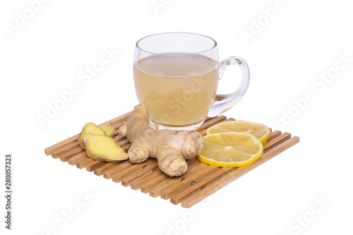 Ginger root tea in glass mug, lemon slices on a bamboo coaster.
