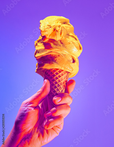 Golden Ice Cream Sugar Cone in Hand on Purple Background Isolated (ID: 280058314)